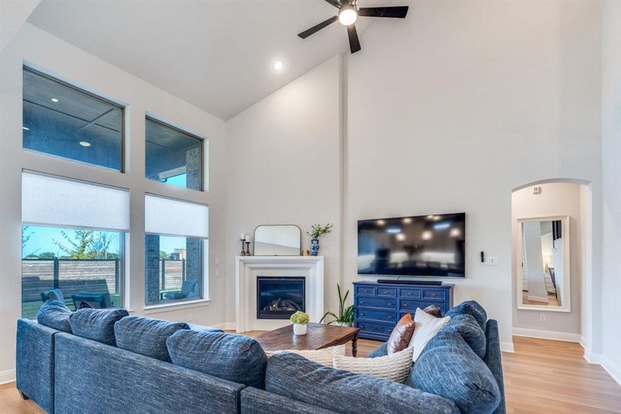 Living area featuring high vaulted ceiling, light wood finished floors, a glass covered fireplace, and recessed lighting