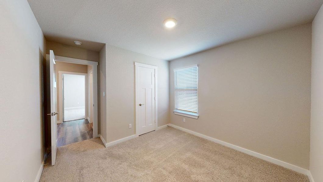 Unfurnished bedroom featuring light carpet and baseboards