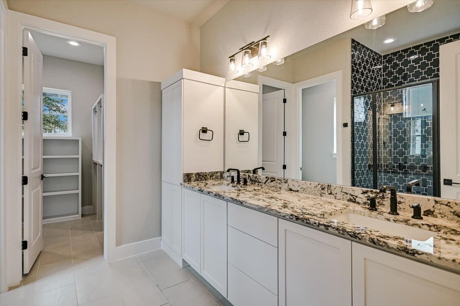 Bathroom with double vanity, light tile patterned floors, a stall shower, recessed lighting, and a walk in closet