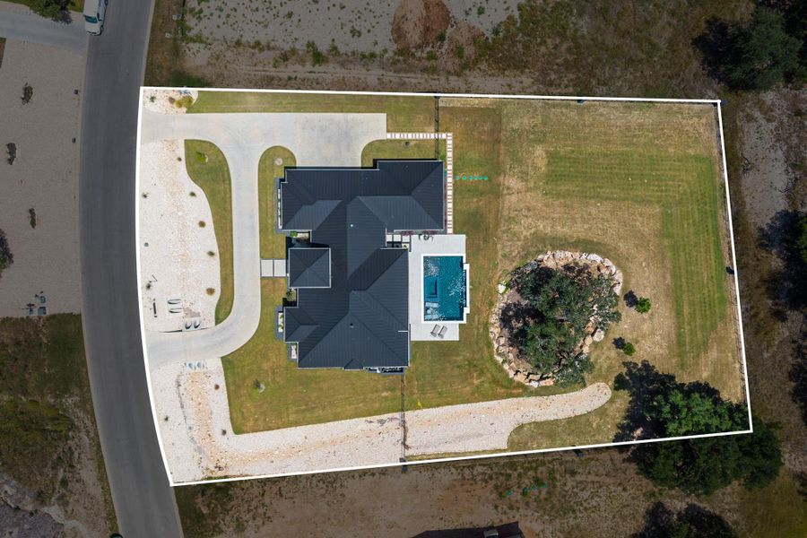An aerial perspective showcases the expansive property boundaries, private pool, and metal roofing.