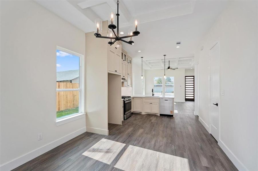 Kitchen featuring light countertops, dark wood-style flooring, suspended lighting, stainless steel appliances, and glass fronted cabinets