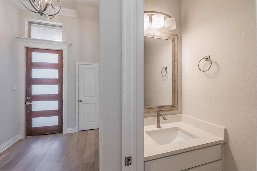 Bathroom with vanity, wood-type flooring, crown molding, and an inviting chandelier