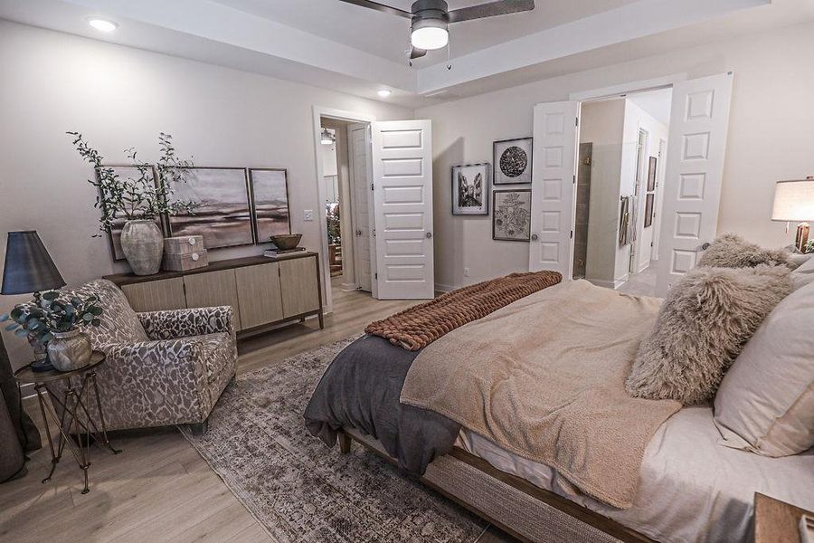 Bedroom with light wood-type flooring, a ceiling fan, and ensuite bathroom