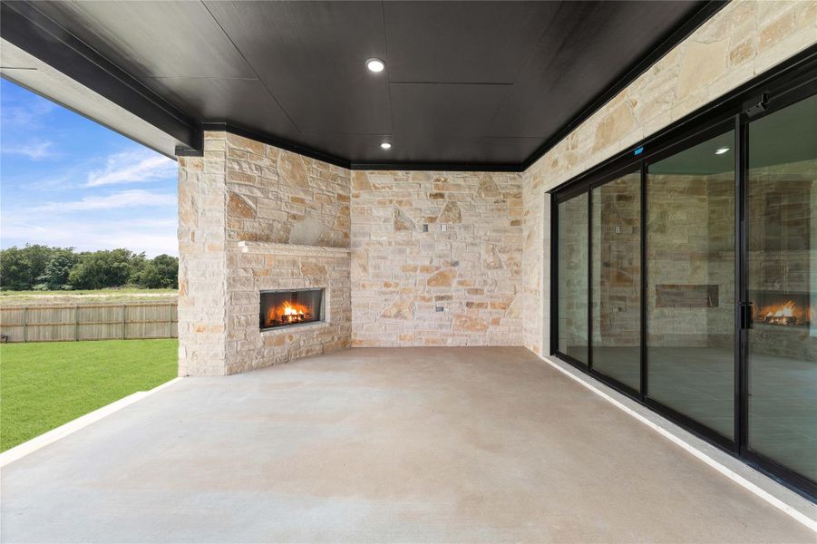 A captivating stone-clad covered patio offers an inviting outdoor fireplace and seamless access to the surrounding landscape. A captivating stone-clad covered patio offers an inviting outdoor fireplace and seamless access to the surrounding landscape.