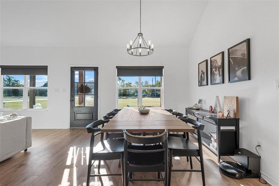 Dining space featuring light wood-style floors, a chandelier, and high vaulted ceiling