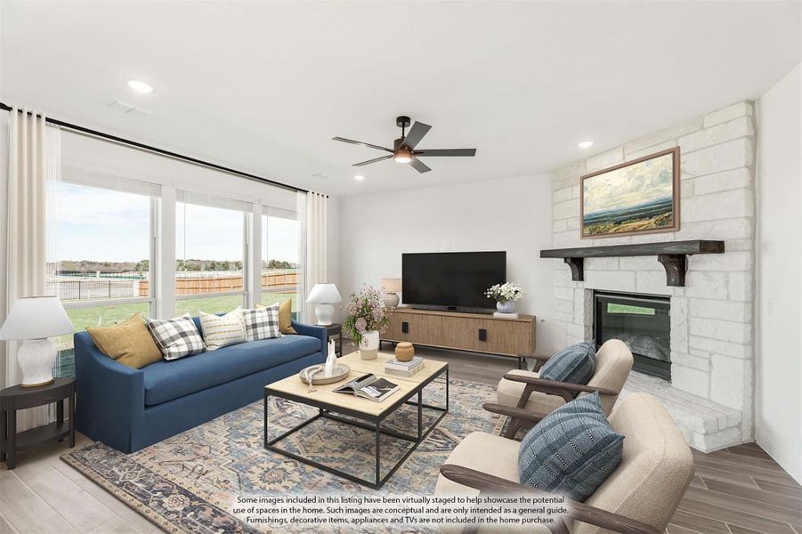 Living room with stone fireplace, ceiling fan, blue sofa, and large windows with backyard view Living room with stone fireplace, ceiling fan, blue sofa, and large windows with backyard view