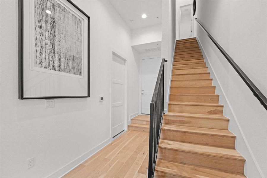 Hardwood staircase featuring black wrought iron railing and white risers