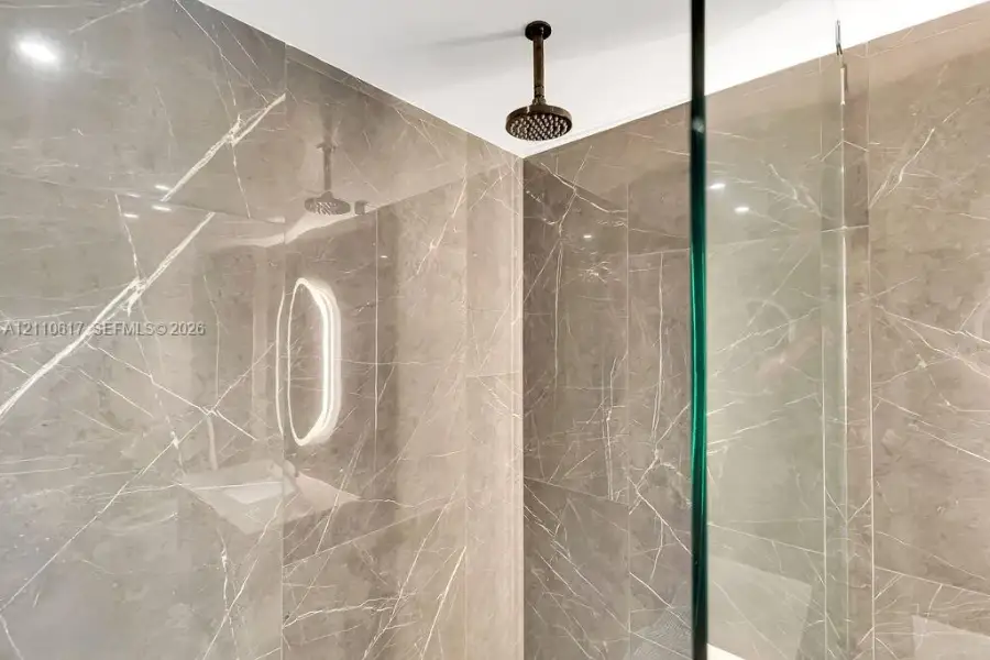Walk-in shower featuring floor-to-ceiling stone-patterned tile, ceiling-mounted rainfall shower head, and glass enclosure Walk-in shower featuring floor-to-ceiling stone-patterned tile, ceiling-mounted rainfall shower head, and glass enclosure