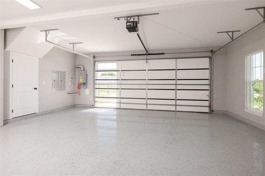 Garage with baseboards, electric panel, and a garage door opener Garage with baseboards, electric panel, and a garage door opener