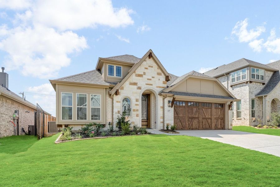 Single-story home with stone and stucco exterior, wood garage door, arched entry, and green front lawn.