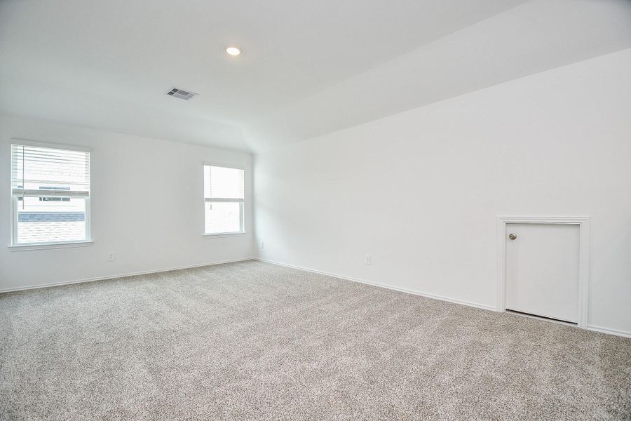 Spacious game room with plush carpeting and bright white walls, perfect for relaxation and entertainment.