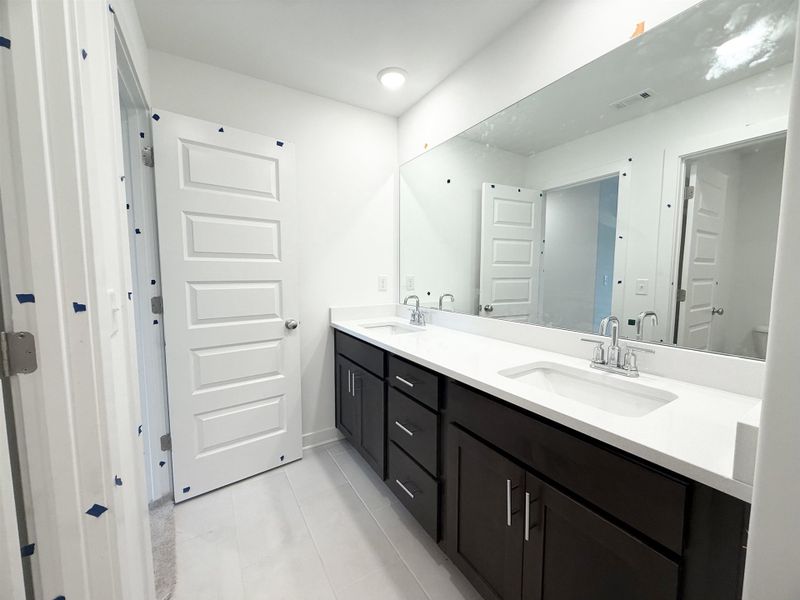 Bathroom featuring double vanity, tile patterned flooring, baseboards, and toilet Bathroom featuring double vanity, tile patterned flooring, baseboards, and toilet