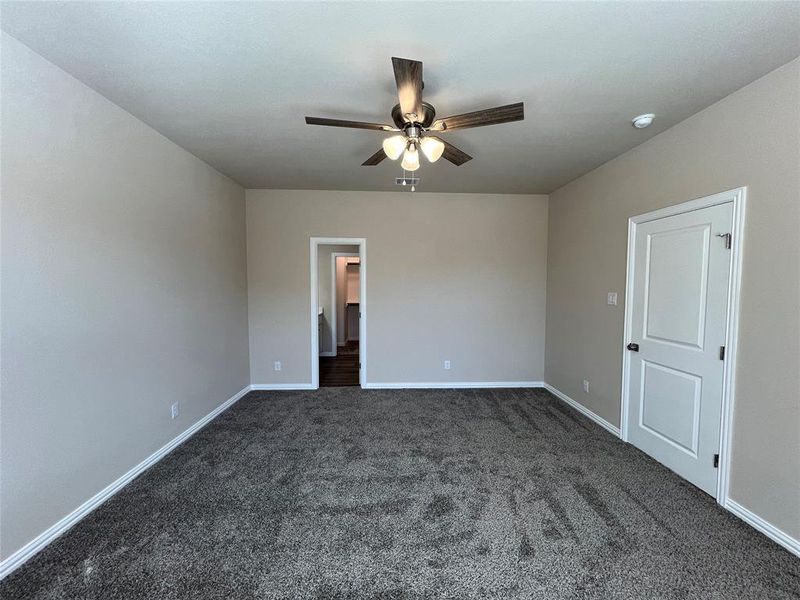 Unfurnished room featuring dark colored carpet and ceiling fan