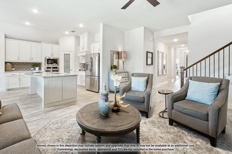 Open-concept living room and kitchen with white cabinets, center island, staircase, and light wood floors Open-concept living room and kitchen with white cabinets, center island, staircase, and light wood floors