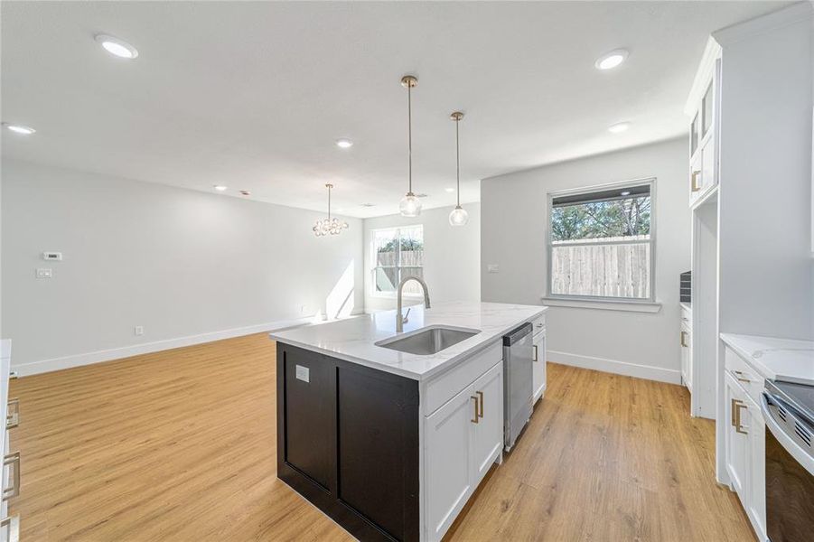 Kitchen with a kitchen island with sink, white cabinets, light wood-type flooring, and recessed lighting Kitchen with a kitchen island with sink, white cabinets, light wood-type flooring, and recessed lighting