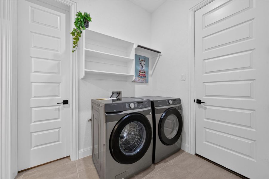 Functional laundry space features with built-in shelving overhead. Functional laundry space features with built-in shelving overhead.