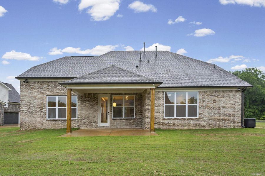 Rear exterior featuring a covered patio with wood columns, brick facade, and a shingle roof Rear exterior featuring a covered patio with wood columns, brick facade, and a shingle roof