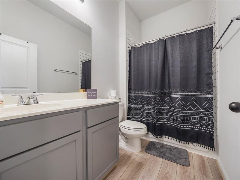 The guest bath offers plenty of space for guests. The shower/tub combo has the elongated subway tiles as well.