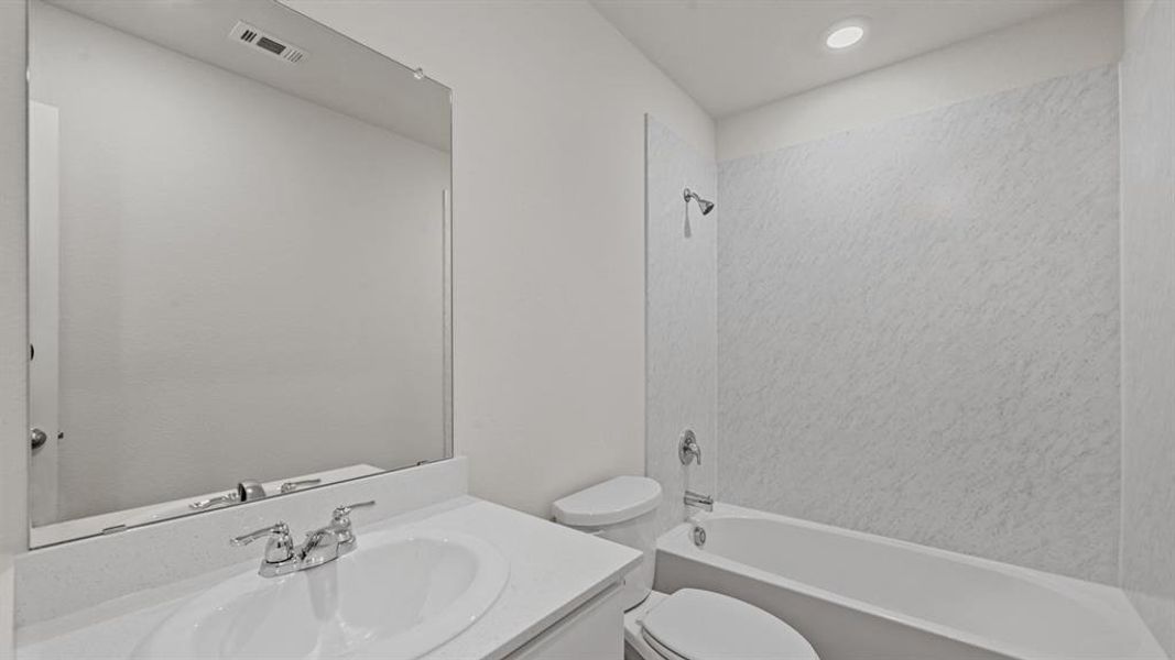 Bathroom featuring a white vanity with an integrated sink, chrome faucet, and a large wall-mounted mirror