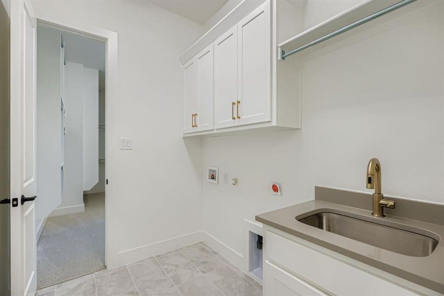 Washroom with gas dryer hookup, cabinet space, hookup for a washing machine, light tile patterned floors, and light colored carpet Washroom with gas dryer hookup, cabinet space, hookup for a washing machine, light tile patterned floors, and light colored carpet