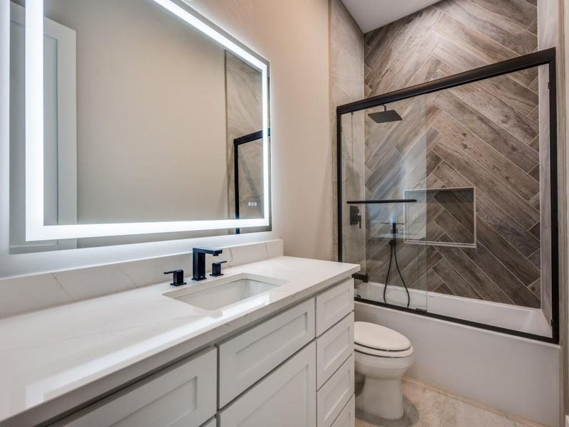 Downstairs guest bath with built in cabinets, Lighted mirror with push button selections for lighting and anti fog, custom herringbone patterned tile surround for shower bath combo.