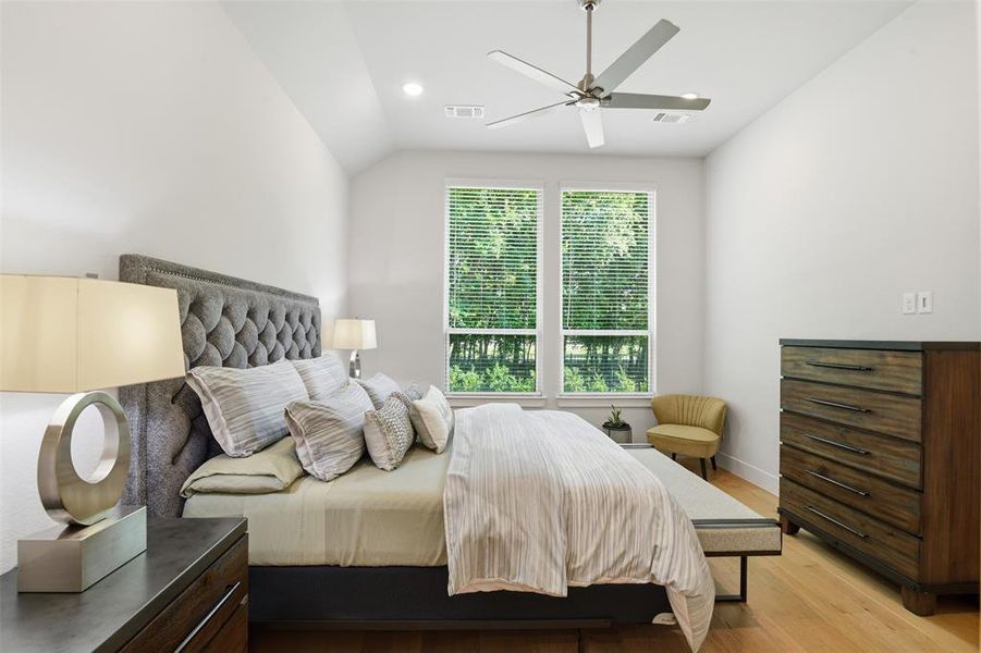 Vaulted ceiling bedroom featuring expansive windows with natural light, a ceiling fan, light wood-finish flooring, and recessed lighting Vaulted ceiling bedroom featuring expansive windows with natural light, a ceiling fan, light wood-finish flooring, and recessed lighting