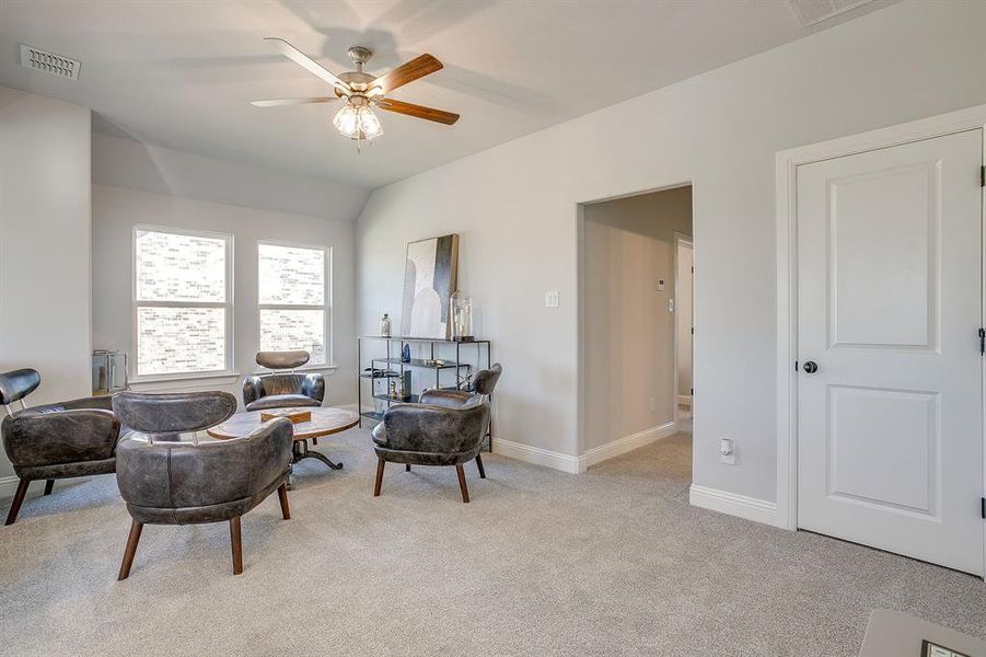 Sitting room with light colored carpet, ceiling fan, and vaulted ceiling