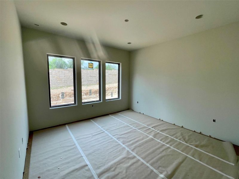 The property features a room with a smooth ceiling, recessed lighting, and three tall windows providing natural light