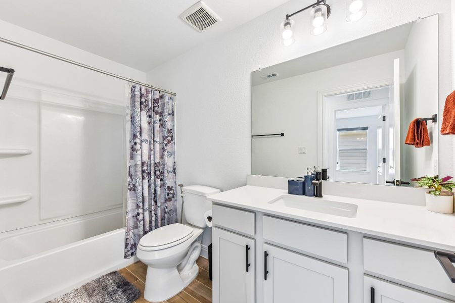 A well-appointed bathroom boasts a bright vanity with ample storage, contrasting dark fixtures, and a clean tub.
