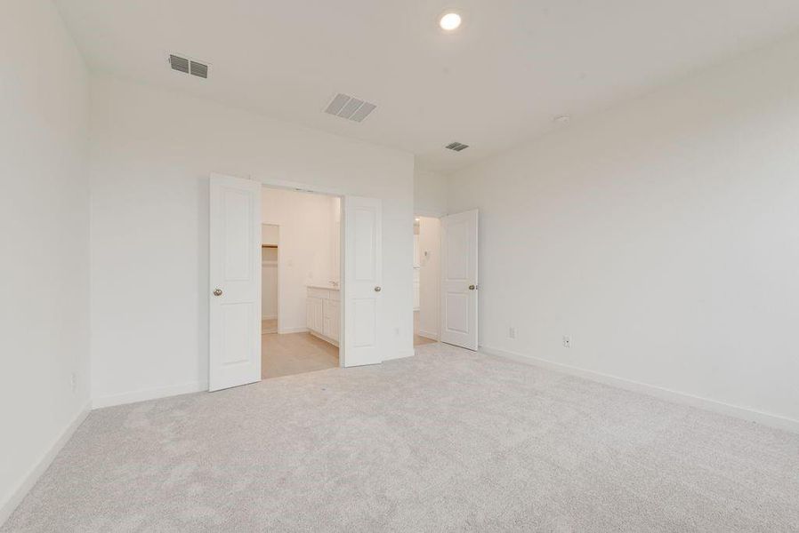 Unfurnished bedroom with light colored carpet, a walk in closet, and recessed lighting