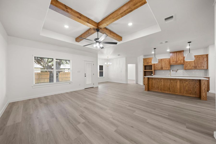 Exposed wood beams adorn the high ceilings of this generously sized, open-concept living space with a large kitchen island. Exposed wood beams adorn the high ceilings of this generously sized, open-concept living space with a large kitchen island.