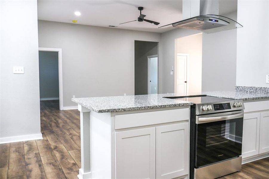Kitchen featuring electric stove, dark wood-style flooring, island exhaust hood, a ceiling fan, and a peninsula