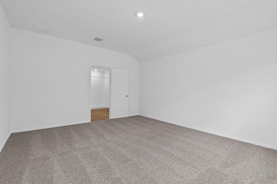 Carpeted empty room featuring vaulted ceiling and baseboards Carpeted empty room featuring vaulted ceiling and baseboards