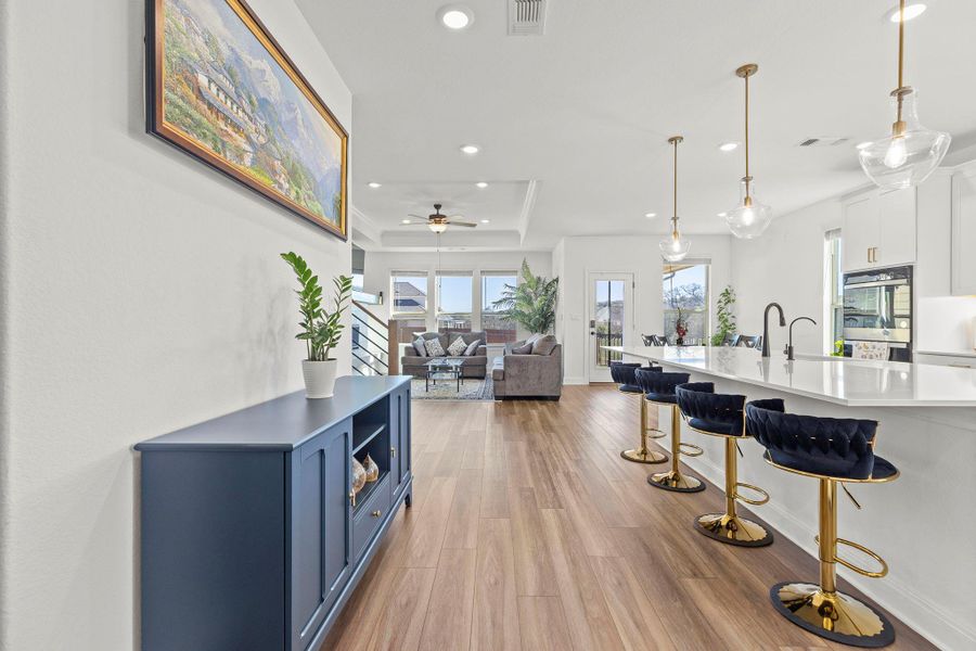 Kitchen featuring open floor plan, dark wood-type flooring, a breakfast bar area, a ceiling fan, and a tray ceiling