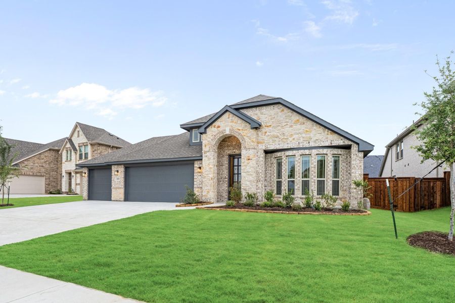 Single-story home with stone exterior, arched entry, two-car garage, and green front lawn Single-story home with stone exterior, arched entry, two-car garage, and green front lawn