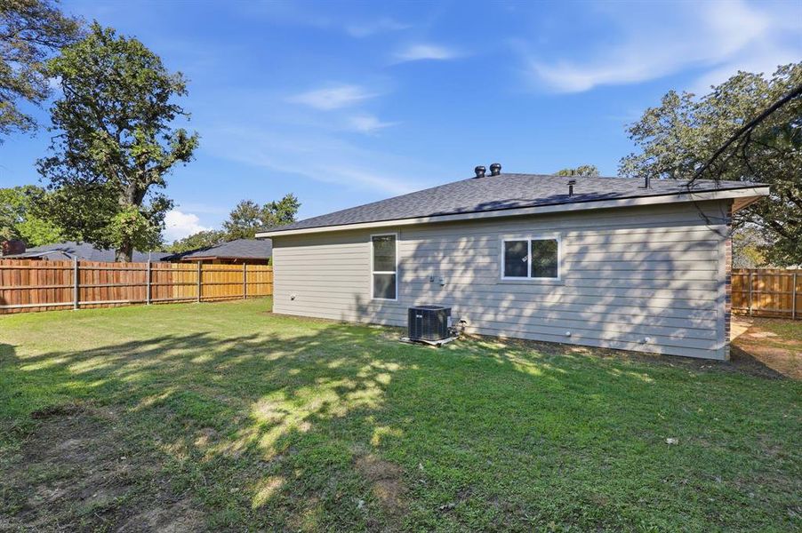 Rear view of house with a fenced backyard and a shingled roof