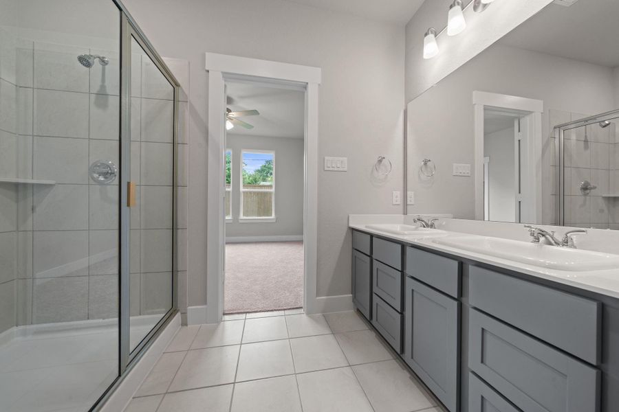 The oversized walk-in shower is enclosed in glass and accented with clean, modern tile, completing the spa-like feel of this luxurious space.