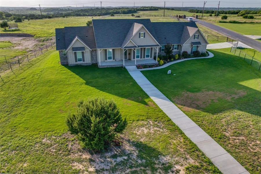 View of front of house with a porch, roof with shingles, and a rural view