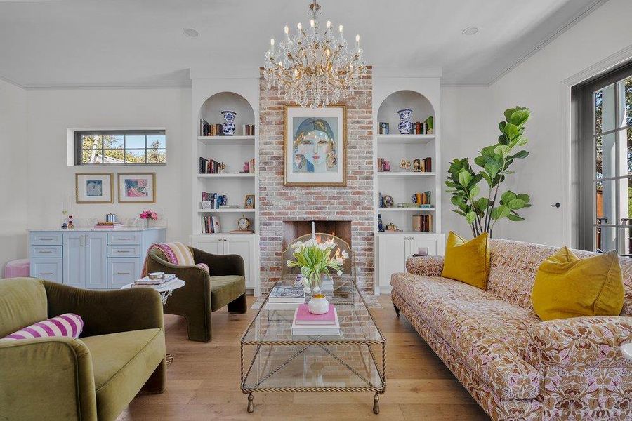 Living area with healthy amount of natural light, suspended lighting, wood finished floors, and ornamental molding