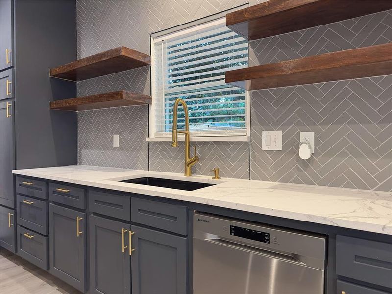 Kitchen featuring sink, dishwasher, light stone counters, and backsplash