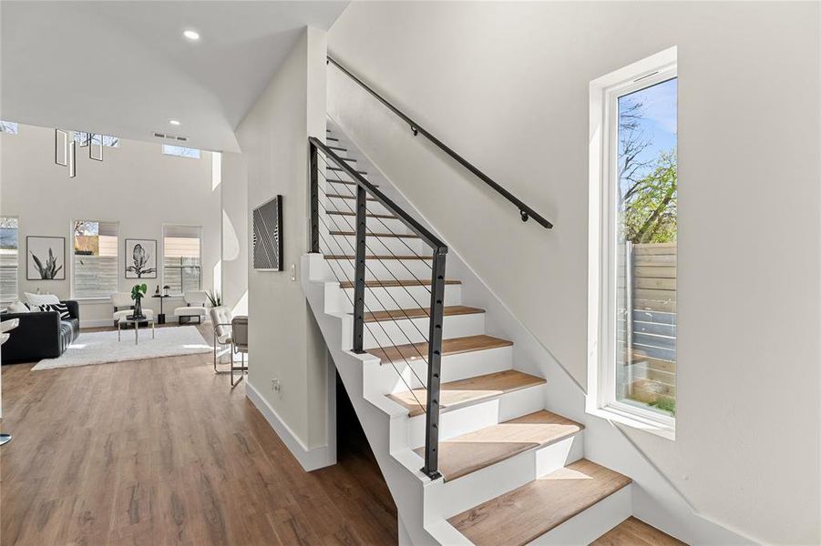 Staircase with wood finished floors, a high ceiling, and recessed lighting