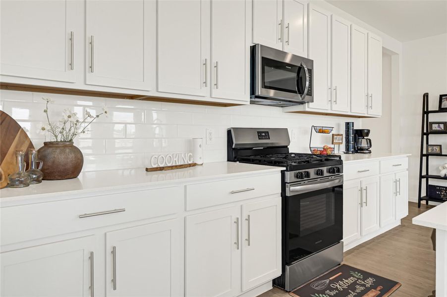 Sleek kitchen with modern stainless steel appliances, bright white cabinetry, and a chic subway tile backsplash. Sleek kitchen with modern stainless steel appliances, bright white cabinetry, and a chic subway tile backsplash.
