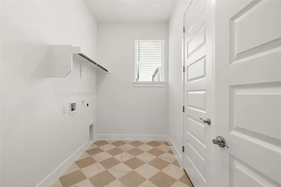 A well-lit laundry area with patterned tile flooring and convenient shelving. A well-lit laundry area with patterned tile flooring and convenient shelving.