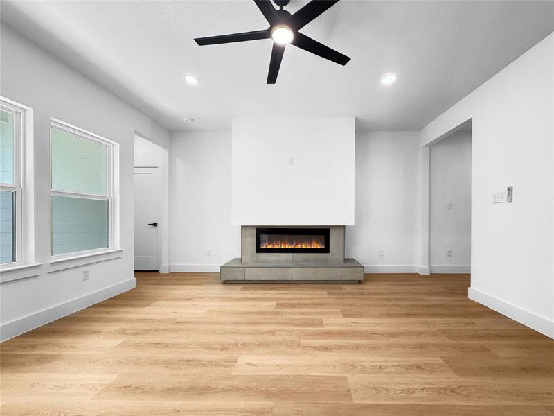 Unfurnished living room with a fireplace, light wood finished floors, recessed lighting, and ceiling fan