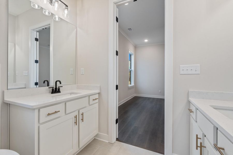 Bathroom with two vanities, ornamental molding, recessed lighting, and light wood-style flooring Bathroom with two vanities, ornamental molding, recessed lighting, and light wood-style flooring