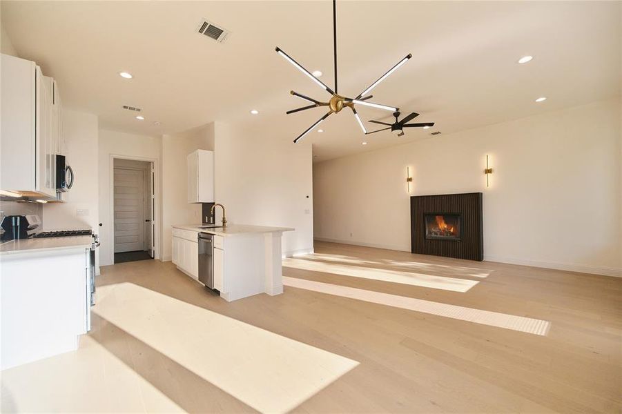 Kitchen featuring light wood-type flooring, white gas stove, white cabinetry, ceiling fan, and stainless steel dishwasher