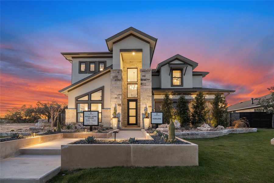 View of house featuring stone siding, stucco siding, and a lawn