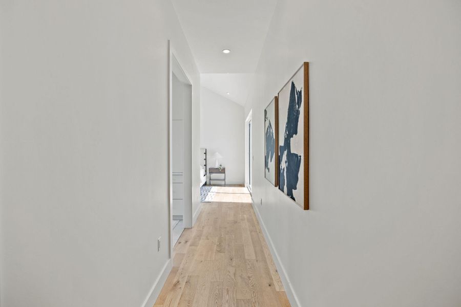 Hall with light wood finished floors, recessed lighting, and lofted ceiling Hall with light wood finished floors, recessed lighting, and lofted ceiling