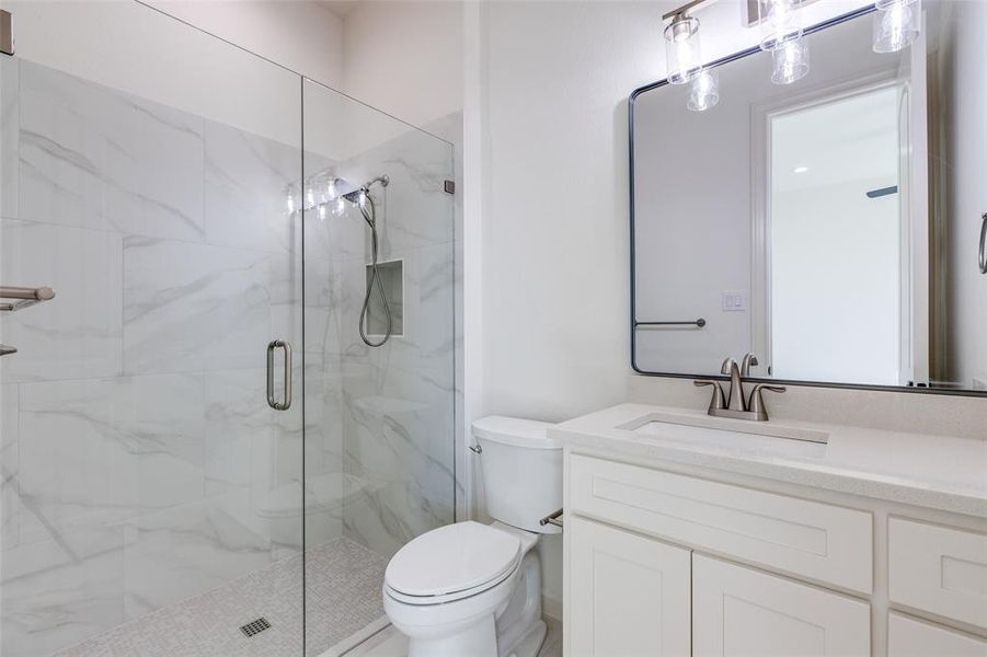 Bathroom featuring vanity, toilet, and an enclosed shower