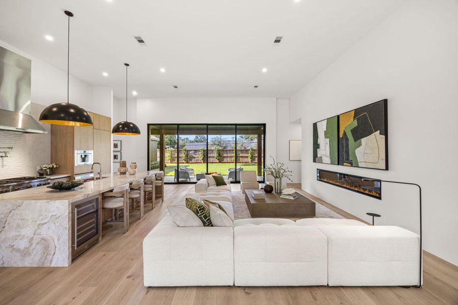 Family Room offers a spacious open area w/ flush in-set fireplace & open chef's kitchen behind it.